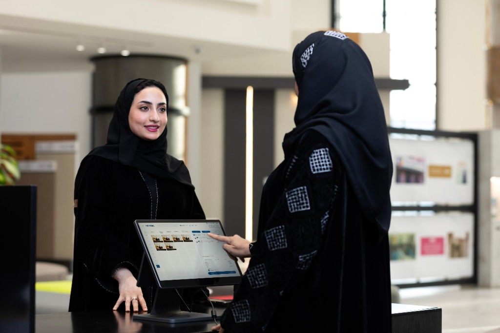 موظفة وعميلة عند نقطة بيع في صالة عرض دهانات الجزيرة؛ شاشة تعرض واجهة ريڤيست